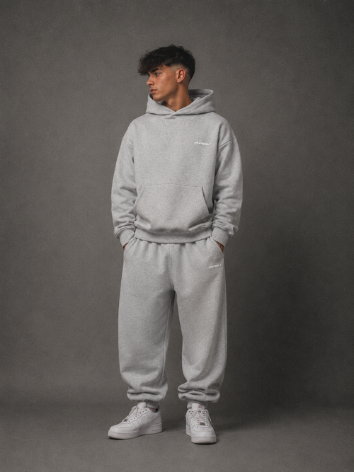 Person wearing a gray hoodie and pants set against a gray background